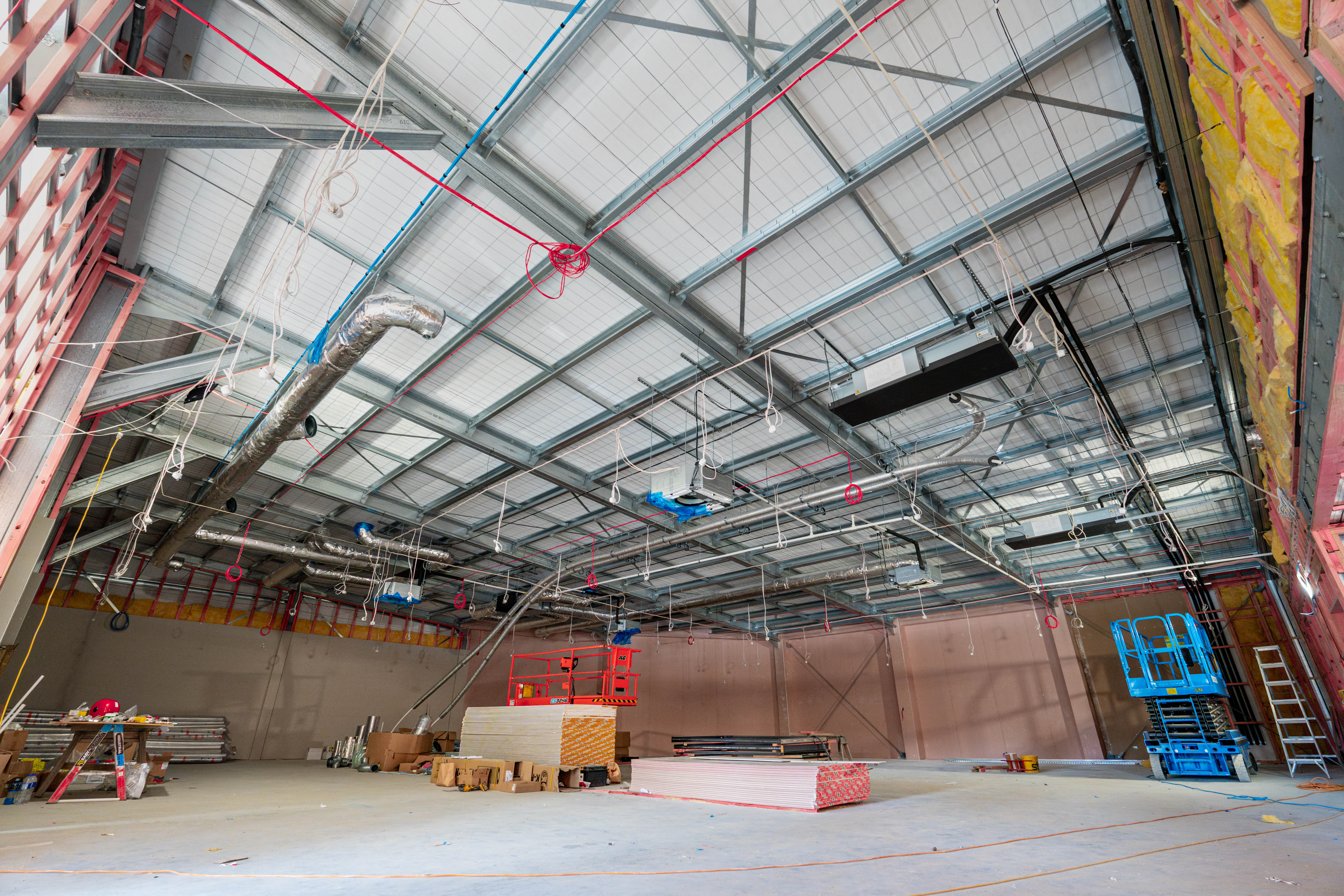Interior during fitout, exposed steel roof and first-fix services