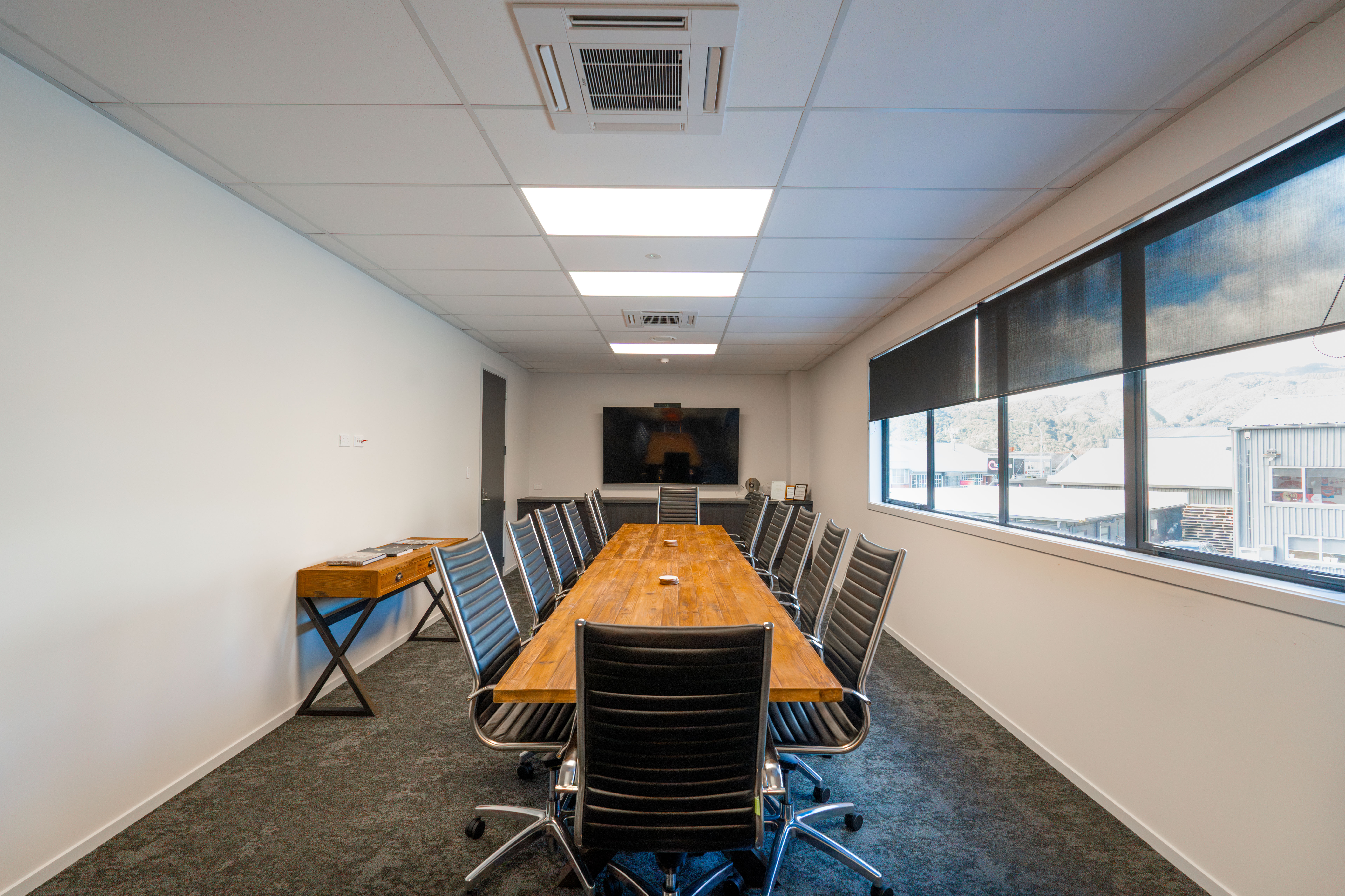 Boardroom with timber table, conditioned by a ceiling cassette unit